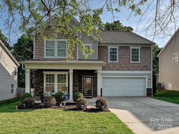 Charming two-story home featuring a stone-accented porch, a two-car garage, and a well-maintained lawn at 1033 Lilly Pond Dr, Fort Mill, SC 29715