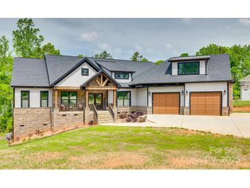 Beautiful two-story home featuring stone accents, a welcoming porch, an attached two car garage, and manicured lawn at 1336 W Rebound Rd, Indian Land, SC 29720