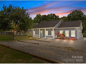 Charming home featuring a gravel driveway, covered front porch, fresh landscaping, and inviting curb appeal at 14532 E Rocky River Rd, Davidson, NC 28036