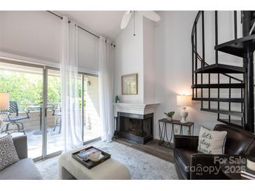 Bright living room featuring a fireplace, spiral staircase, and sliding glass doors to the deck at 2504 Stradbrook Dr # B, Charlotte, NC 28210