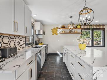 Bright kitchen featuring marble countertops, stainless steel appliances, and modern black and white backsplash at 2701 N Sharon Amity Rd, Charlotte, NC 28205