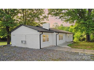 Charming white brick ranch home with a black roof and a large gravel driveway at 5520 Chestnut Dr, Hickory, NC 28602