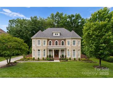Beautiful stone and brick home with a manicured lawn and mature trees at 7005 Camrose Crossing Ln, Matthews, NC 28104