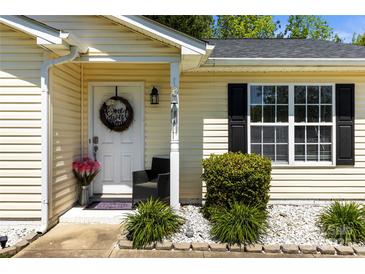Charming home entrance with a welcoming wreath, black chair, and well-manicured landscaping at 119 Sweet Martha Dr, Mooresville, NC 28115