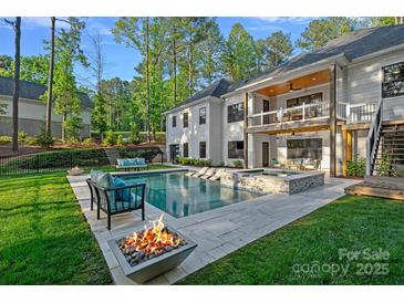 Beautiful backyard featuring a pristine pool, a cozy fire pit, and an elegant two-story home with a balcony at 127 Holt Ln, Mooresville, NC 28117