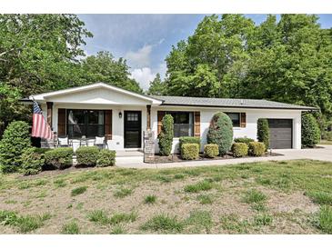 Charming single-story home with a landscaped yard, inviting front porch, and attached garage at 202 Hickory St, Locust, NC 28097