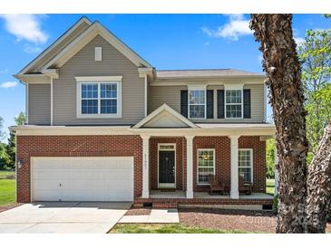 Charming two-story home featuring a brick facade, a welcoming front porch with rocking chairs, and a well-maintained lawn at 21907 Torrence Chapel Rd, Cornelius, NC 28031