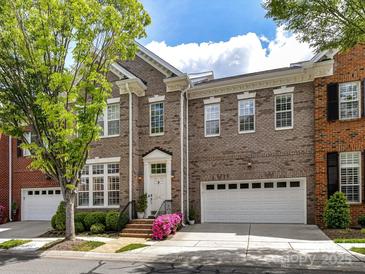 Charming brick townhome featuring manicured landscaping, attached garage, and inviting front entrance with colorful flowers at 6133 Wakehurst Rd, Charlotte, NC 28226