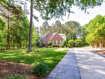 Charming brick home with lush landscaping, mature trees and a beautiful stone walkway at 3519 Weddington Oaks Dr, Matthews, NC 28104
