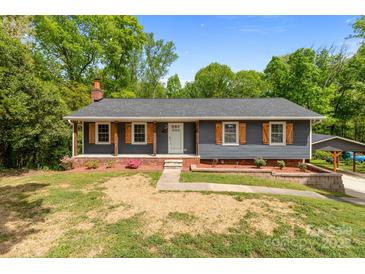 Charming single story home with a brick foundation, gray siding, and lovely wood shutters at 4050 Leafmore St, Concord, NC 28027