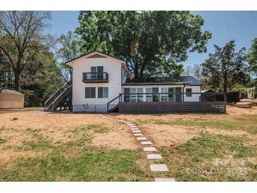 Charming waterfront home featuring a spacious deck and stepping stone pathway to the lawn at 451 S Strand Dr, Norwood, NC 28128