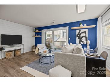 Bright living room with modern furniture, blue accent wall, balcony access, and contemporary decor at 505 N Graham St # 2H, Charlotte, NC 28202
