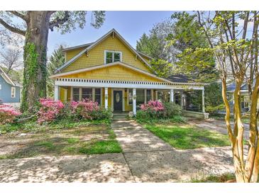 Charming two-story yellow home featuring a welcoming front porch and beautiful landscaping at 505 S South St, Gastonia, NC 28052
