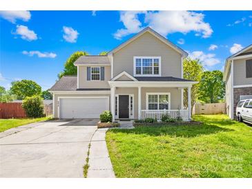 Charming two-story home featuring a covered front porch, attached garage, and well-maintained lawn on a sunny day at 6418 Castlewynd Ct, Charlotte, NC 28212