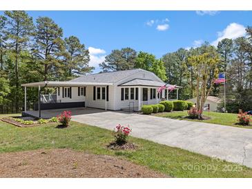 Charming home with a covered carport, landscaped yard, and American flags displayed at 8044 Eagle St, Mount Pleasant, NC 28124