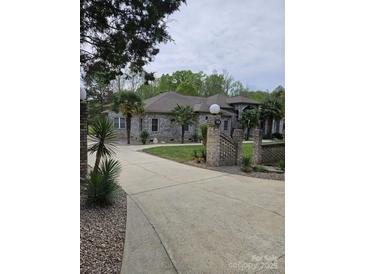 Attractive one-story home with brick exterior, driveway, manicured lawn, and palm trees at 9535 Potter Rd, Matthews, NC 28104
