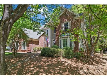 Charming two-story brick and gray home with mature trees and landscaping creating a serene and inviting atmosphere at 15744 Berryfield St, Huntersville, NC 28078