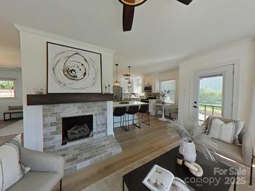 Open-concept living room featuring a brick fireplace and seamlessly flowing into a modern kitchen with a breakfast bar at 2138 Revolution Park Dr, Charlotte, NC 28208
