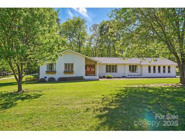 Charming single-story home with mature trees and a lush, green front lawn at 4307 Wrangler Sw Dr, Concord, NC 28027