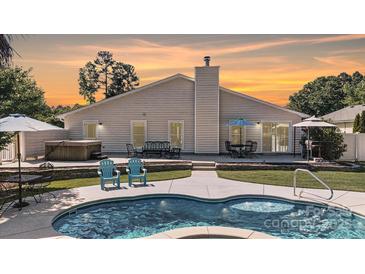 Gorgeous kidney-shaped pool with poolside lounge area and a hot tub, perfect for outdoor entertaining at 7018 Huntsmaster Dr, Charlotte, NC 28277