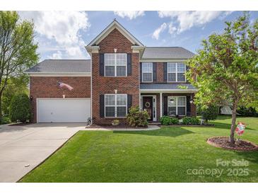 Charming two-story brick home featuring a manicured lawn, attached two car garage, and tasteful landscaping at 1002 Banaba Dr, Indian Trail, NC 28079
