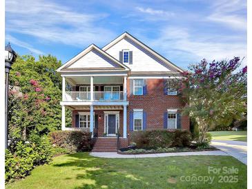Charming two-story brick home with a covered front porch and lush landscaping under a bright blue sky at 1105 Hoyle Ln, Waxhaw, NC 28173