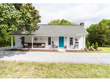 Charming home featuring a welcoming front porch with rocking chairs and a bench, complemented by a blue front door and landscaped yard at 1165 Old Salisbury Concord Rd, Concord, NC 28025