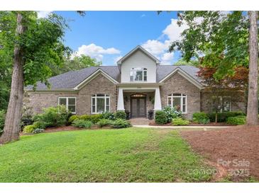 Charming brick home featuring a manicured lawn and well-maintained landscaping, with flowering bushes in the front yard at 206 Oxford Place Dr, Fort Mill, SC 29715