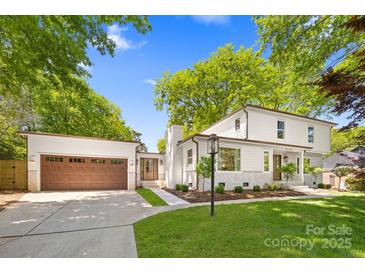 Charming white home featuring an attached garage, manicured lawn, and professionally landscaped front yard at 2411 Ainsdale Rd, Charlotte, NC 28226