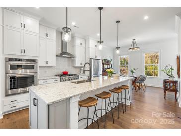 Bright kitchen features a large island with bar stool seating, modern appliances, and white cabinetry at 2558 Deacon Ave, Charlotte, NC 28204