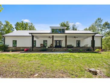 Charming farmhouse featuring a white exterior, metal roof, and inviting front porch with chairs and swing at 29268 Pennington Rd, Albemarle, NC 28001