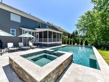 Gorgeous backyard pool and spa area with beautiful landscaping, outdoor seating and screened in porch at 3057 Drummond Ave, Indian Land, SC 29707