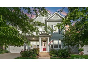 Charming two-story home featuring a red front door, manicured lawn, and an inviting porch with an American flag at 5301 Meadowcroft Way, Fort Mill, SC 29708