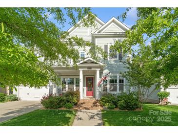 Charming two-story home featuring a red front door, manicured lawn, and an inviting porch with an American flag at 5301 Meadowcroft Way, Fort Mill, SC 29708