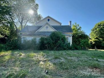 Exterior shot of home with overgrown lawn and mature trees on a sunny day at 6000 S Main St, Salisbury, NC 28147