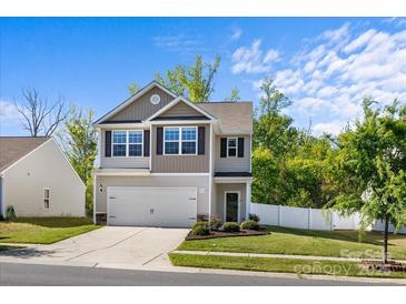 Charming two-story home boasts a landscaped yard, attached garage, and neutral-tone siding beneath a clear blue sky at 7113 Amberly Hills Rd, Charlotte, NC 28215