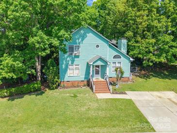 Charming two-story home with a blue exterior, brick stairs, and a lush green lawn, nestled among mature trees at 9012 Windjammer Dr, Tega Cay, SC 29708