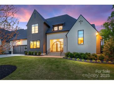 Elegant home with a manicured lawn, striking architecture, and a grand entrance, bathed in the soft hues of dusk at 1118 Jefferson Dr, Charlotte, NC 28270