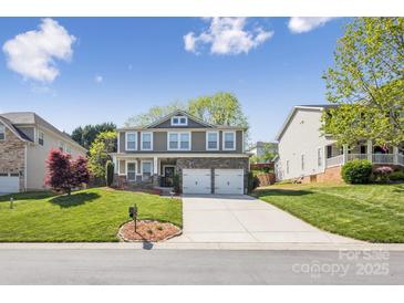 Charming two-story home featuring a stone accent facade, manicured lawn, and a two-car garage at 117 Tom Sawyer Ln, Mount Holly, NC 28120