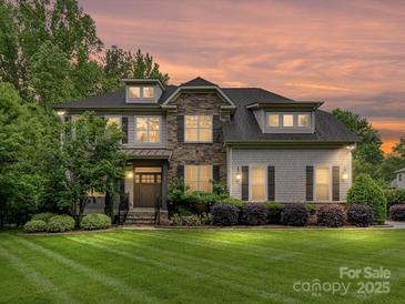 Beautiful two-story home showcasing stone accents, dormer windows, professional landscaping, and a well-manicured front lawn at 7809 Greenfield Dr, Charlotte, NC 28270