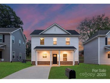 Charming two-story home featuring a covered front porch and a well-maintained lawn at dusk at 1841 Bear St, Charlotte, NC 28213