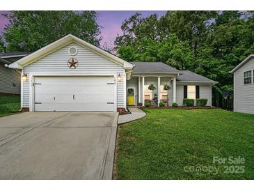 Charming single-story home with a well-manicured lawn, attached garage, and inviting front porch with rocking chairs at 7417 Chidley Dr, Charlotte, NC 28269