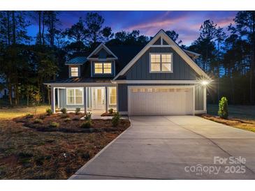 Charming home with a manicured lawn, a two-car garage, and a cozy front porch, illuminated against a twilight sky at 925 Twin Lakes Rd, Rock Hill, SC 29732