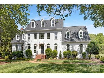 Stately white home featuring dormer windows, black door, brick walkway, and manicured lawn at 426 Walden Trl, Waxhaw, NC 28173