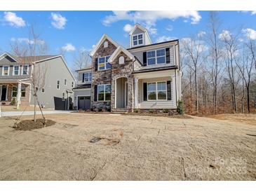 New two-story home featuring a stone facade, neutral siding, dark shutters, and an attached two-car garage at 5031 Mclaughlin Loop # 60, Waxhaw, NC 28173