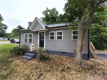 Charming one-story home with gray siding, black door and steps, and front yard with tree and flowers at 589 Fork Rd, Norwood, NC 28128