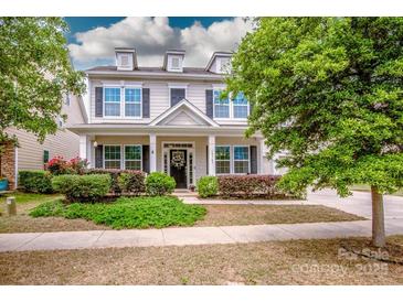 Charming two-story home with a well-manicured lawn, dormer windows, and inviting front porch at 10707 Charmont Pl, Huntersville, NC 28078