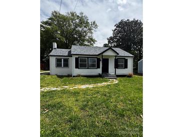 Charming home features a white exterior, black trim, a gray roof and a well-maintained lawn at 1104 Linwood Rd, Gastonia, NC 28052