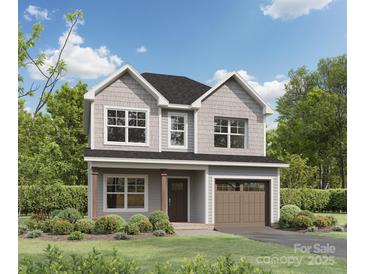 Charming two-story home boasts a shingle facade, attached garage, and professionally landscaped front yard at 1142 Forest Dr, Marshville, NC 28103