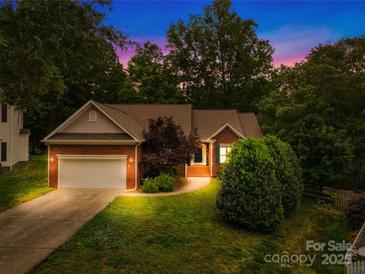 Charming brick home featuring a well-manicured lawn and an attached two-car garage at dusk at 11732 Borchetta Dr, Charlotte, NC 28277